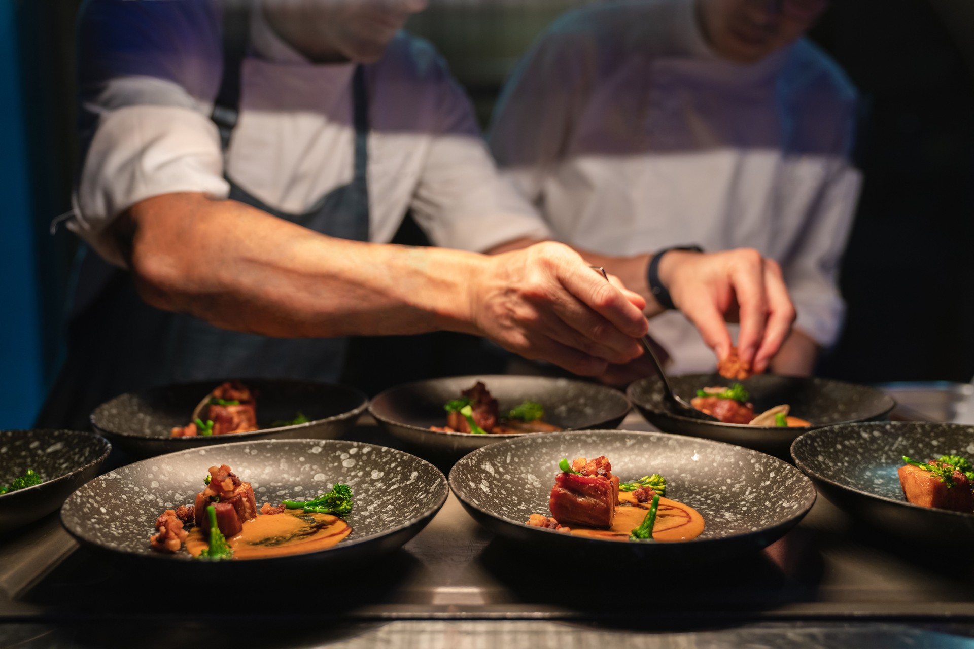 Chefs preparing food in professional kitchen.